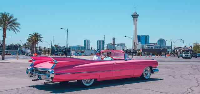 Old school car with city view in background.